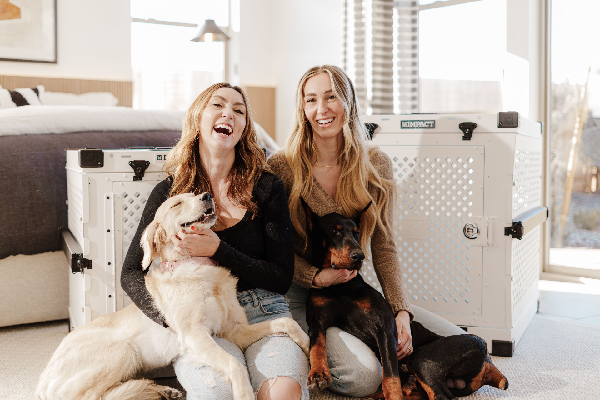 Two friends sitting together at home with their dogs, laughing